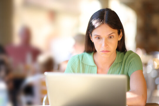 Perplexed woman checking laptop in a restaurant