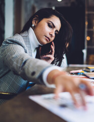 Fototapeta premium Serous female calling on smartphone taking document at workplace