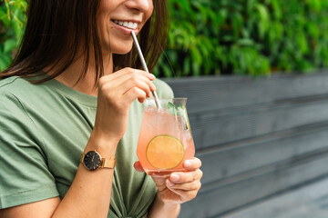 Happy woman with beautiful smile drinking fresh and iced paloma cocktail 