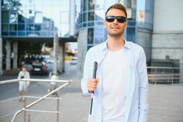Portrait of a young, handsome blind man walking in the city. The concept of limited physical...