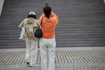 観光地で記念写真を撮影している女性観光客の後姿