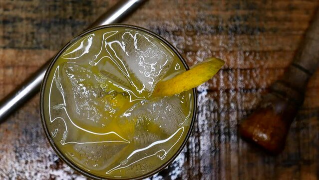  Person placing a caipirinha on the table. A cacha&ccedil;a and lemon caipirinha on a wet wooden table. Brazilian caipirinha drink recipe: sugarcane liquor, sugar, ice, lemon slices. Making cocktails. Bar 