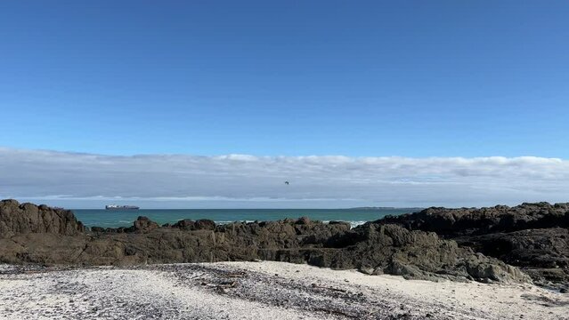 Ships out at sea and views of Robben Island from a rocky shoreline