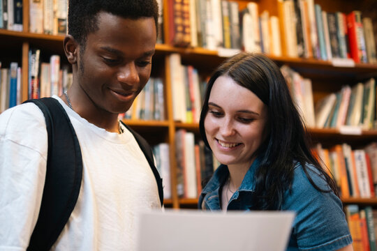 Happy man and woman reading document in library