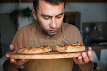 Man smelling baked pie on cutting board