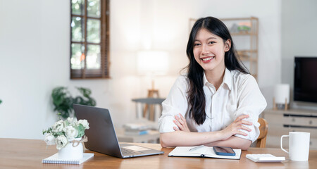 Young beautiful joyful woman smiling while working with laptop in office