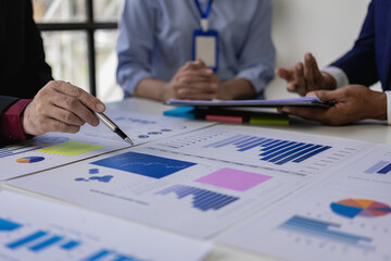 Close-up of a business team sitting at a desk in front of a laptop with a financial infographic and financial document of a startup company brainstorming a new project in a coffee shop.