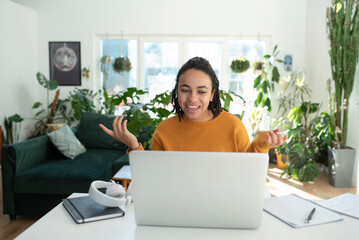 Happy businesswoman gesturing on video call through laptop at home office