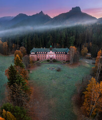 Jetrichovice, Czech Republic - Aerial view of beautiful pink mansion near Jetrichovice at sunrise on a foggy autumn morning with Mariina vyhlidka viewpoint at background in Bohemian Switzerland region - obrazy, fototapety, plakaty