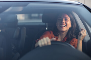 Photo of positive cheerful girl funky driver rider enjoy drive ride car under pop star hits playlist music try dance raise hands in city center - obrazy, fototapety, plakaty