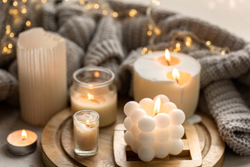 Fototapeta na wymiar A cozy composition with candles, a knitted element and a garland.