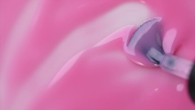 Gel nail polish, pink shellac UV gel brush, varnish, manicure concept, slow motion. Manicure salon, shellac texture background, backdrop. Top view