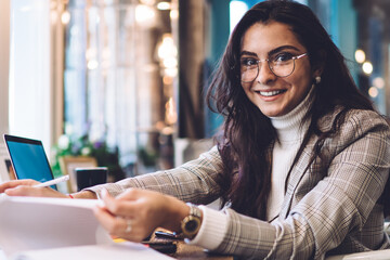 Smart woman in glasses turning pages of notebook