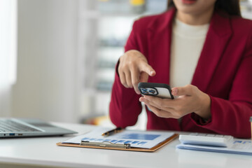 Fototapeta premium A young Asian real estate agent is reviewing documents and calculating interest rates to inform tenants of monthly installments before entering into contracts to buy or sell real estate.