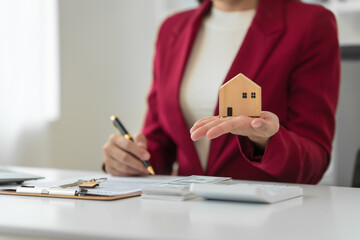 A young Asian real estate agent is reviewing documents and calculating interest rates to inform...