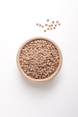 lentils in wooden bowl on white background shot from above