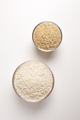 brown rice in glass bowl on white background shot from above