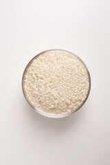white rice in round glass bowl top view on white background