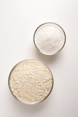 white rice and rice flour in glass bowl on white background shot from above