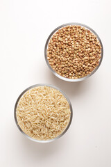 buckwheat and brown rice in glass bowl on white background shot from above