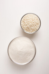 white rice and rice flour in glass bowl on white background shot from above