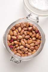 beans borlotti in a glass jar taken from above on a white background