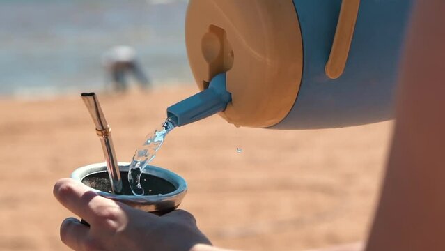 An image depicts the pouring of water into a traditional terer&eacute; gourd, showcasing the cherished ritual of preparing and enjoying this refreshing South American drink.