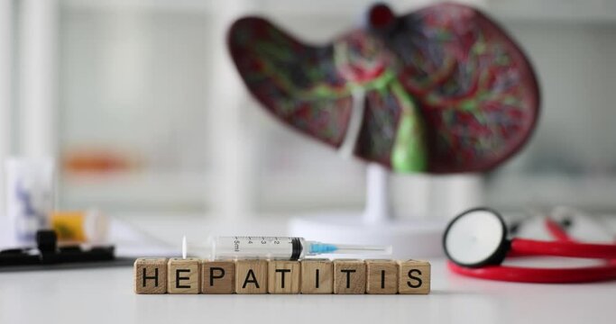 Word hepatitis on background of artificial model of human liver closeup 4k movie. Vaccination and treatment of diseases of liver and biliary tract concept
