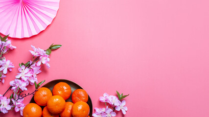 Chinese or lunar new year flat lay with paper decorations, mandarins and flowers on pink