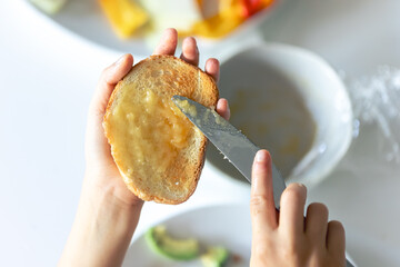Woman spreading jam on toast over table.