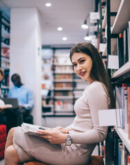 Optimistic lady with book sitting in library