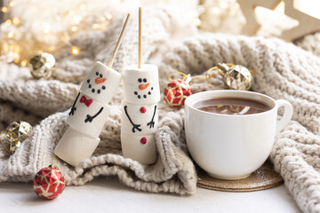 Winter composition with a cup of cocoa and marshmallows on a blurred background.
