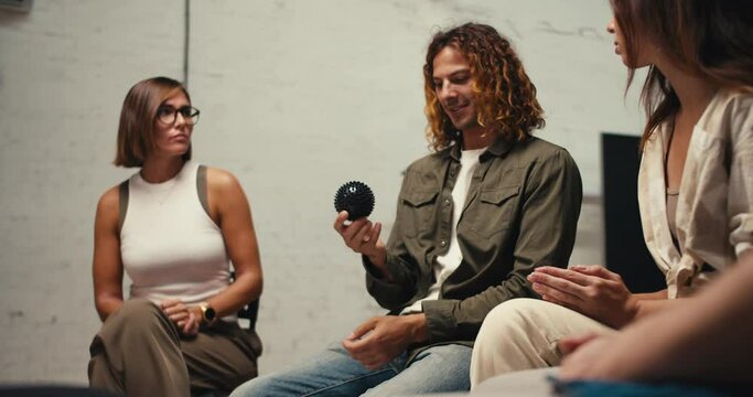 Participants pass each other a black ball and tell each other about themselves. A man with curly hair and a brunette girl. Getting to know each other in group therapy