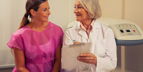 Happy mature woman doctor showing bone densitometer exams to her woman patient in 40s