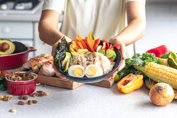 Homemade bowl with rice, vegetables and eggs in female hands.
