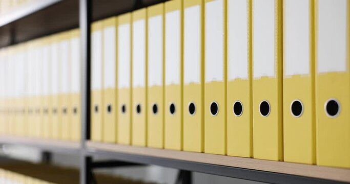 Bookshelf with many yellow document folders closeup 4k movie slow motion. Paper work in archive concept