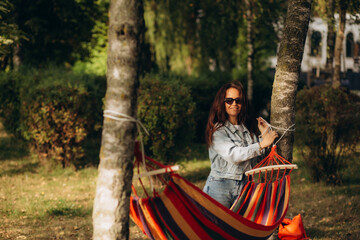 woman ties up hammock in forest between trees