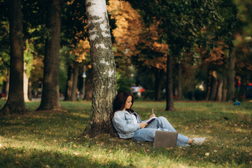 Fototapeta premium woman under tree with laptop and notepad