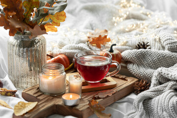 Autumn composition with a cup of tea, leaves and a knitted element.