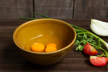 Fresh natural eggs in a bowl with spring onions and coriander to prepare for fried eggs, omelettes