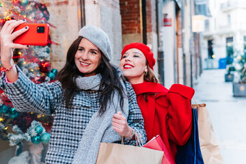 Friends shopping at Christmas sales taking a selfie. Friendship and winter concept