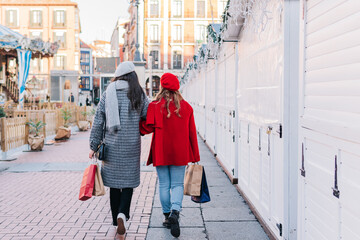 Anonymous female friends with shopping bags on the street in winter. Christmas and sales concept.