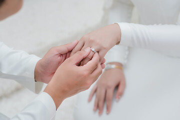 Close up hand groom wearing wedding rings to left finger of bride, Muslim wedding, Wedding Poster,...