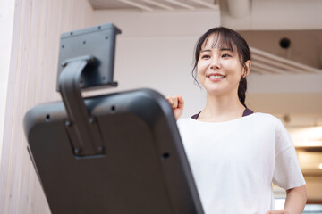 スポーツジムのランニングマシンで運動する女性（健康・ダイエット）