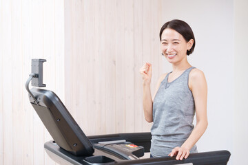 スポーツジムのランニングマシンで運動する女性（健康・ダイエット）