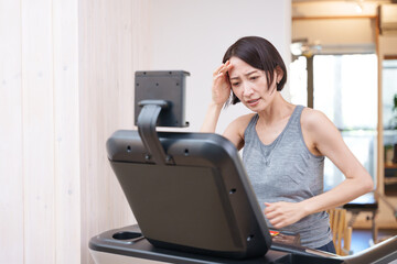 スポーツジムのランニングマシンで運動する女性（健康・ダイエット）