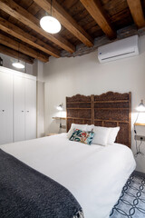 Bedroom interior decorated in rustic style with wooden ceiling and lamps illuminating the room
