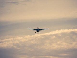 Fototapeta na wymiar Man sieht ein kleines Flugzeug von hinten wie es in den ruhigen Abendhimmel aufsteigt und in die Ferne fliegt.