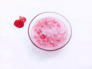 Obraz na płótnie Canvas smoothie in glass. Candil porridge, a traditional snack made from starch and then eaten with coconut milk. chewy, sweet and savory. pink snacks. Bubur candil on white background