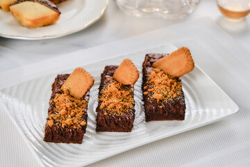 A decadent chocolate brownie sits on a white plate, accompanied by a steaming cup of English tea. The white tablecloth is spotless, adding to the elegant atmosphere.